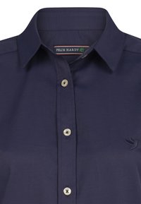 Camicia button-up blu navy con colletto classico, bottoni di colore chiaro e un piccolo dettaglio ricamato di un uccello sul lato sinistro.