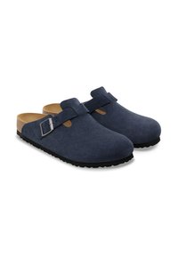 Sabots en daim bleu marine avec une finition lisse, dotés d'une sangle à boucle et d'une semelle intérieure en liège légère, reposant sur une semelle en caoutchouc noire.