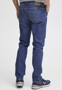 Blå denimjeans med vanlig passform, som har en medelhög midja, två bakfickor med dekorativt stygn och ett subtilt strukturerat tyg.