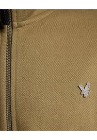 Felpa zip con texture a coste di colore khaki, con logo d'aquila argentato sul lato sinistro vicino alla zip. Collo alto e zip robusta.