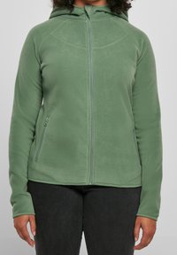 Giacca zip-up in pile di colore verde chiaro, con cappuccio, zip frontale e tasche laterali. Tessuto morbido con un design aderente.
