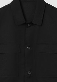 Camicia nera con bottoni, realizzata in tessuto liscio, con colletto e due tasche sul petto, caratterizzata da chiusure a bottone in un design elegante.