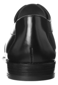 Scarpe in pelle nera con una texture liscia e lucida, tacco arrotondato e dettagli di cucitura minimi su un design elegante.
