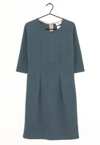 Szydełkowana sukienka w odcieniu zielonego na trzy czwarte rękawów, z zaokrąglonym dekoltem, o fakturowanej tkaninie i poziomej szwie biegnącej pionowo wzdłuż przodu.
