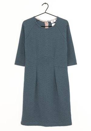 Gebreide teal jurk met driekwart mouwen, ronde halslijn, gestructureerde stof en een naaddetail dat verticaal over de voorkant loopt.