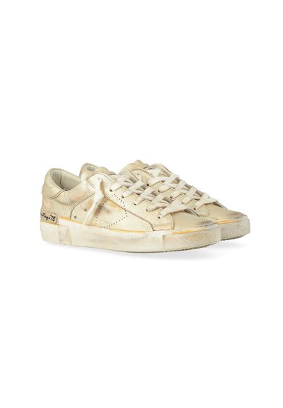 Un paio di sneaker in pelle bianca sporca con lacci bianchi, suole leggermente usurate e testo "vintage 78" sul lato vicino al tallone.