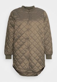 Giacca trapuntata verde oliva con scollo tondo, chiusura con bottoni a pressione e polsini a coste. Presenta una parte posteriore leggermente allungata e cerniere laterali.