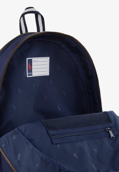 Marine rugzak interieur met een ritsvak en een gaassectie. Met logo label, subtiele patroonvoering en gouden ritsdetails.