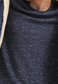 Pull-over couleur bleu marine en tricot texturé, avec une coupe décontractée et un léger motif moucheté dans tout le vêtement.