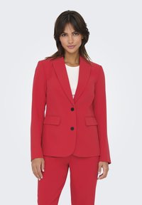 Blazer ajusté rouge en tissu lisse, avec une coupe à un bouton, des revers crantés, deux poches avant et des boutons noirs.