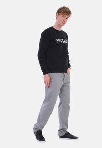 Schwarzer Herren-Sweatshirt mit "PICALDI" Schriftzug, graue Hose und schwarze Sneaker. Lässiges Design, weicher Stoff und taillierte Form.
