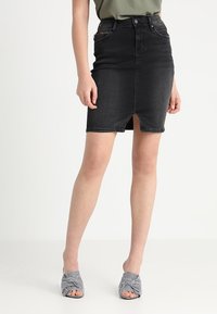 Černá džínová tužková sukně s předním rozparkem, vysokým pasem a klasickým designem s pěti kapsami. Vybavena pruhovanými otevřenými sandály.