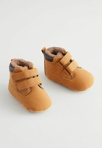 Braune Kunstleder-Stiefel für Kleinkinder mit weichem Futter aus Fell, runder Zehenform und zwei verstellbaren Klettverschlussriemen für einen sicheren Sitz.