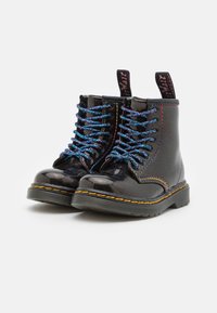 Botas de charol negro con cordones coloridos y brillantes, costuras amarillas y suela de goma gruesa; con tirador en la parte posterior.