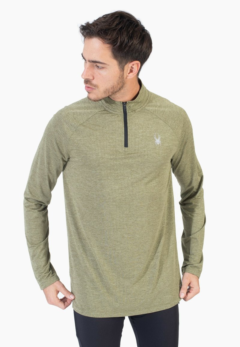 Camisa de manga larga verde con cremallera de un cuarto, fabricada con tejido texturizado y un logo en el pecho. Presenta mangas raglán y dobladillo recto.