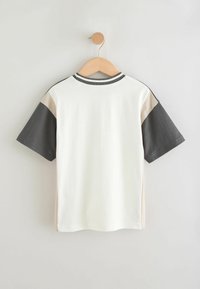 T-shirt a maniche corte con un corpo bianco, maniche grigio scuro e beige, e un collo a coste. Tessuto in cotone con una texture liscia.