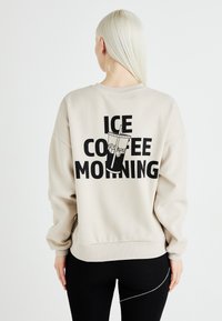 Bežna oversized trenerka z black grafiko kozarca z ledom in napisom "ICE COFFEE MORNING" na hrbtni strani.