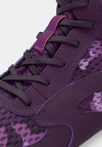 Lilla spordijalats võrgust paneelidega, tekstuursete nööride ja kontrastsete roosade detailidega. Iseloomustab sile sünteetiline materjal ja pehmendatud krae.