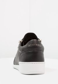 Černé kožené tenisky s texturovaným povrchem, bílou gumovou podrážkou a zipem na patě. Na zadní straně je vyražené logo "ANTONY MORATO".