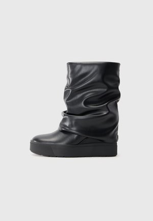 Stivale alla caviglia in pelle nera con design morbido, punta tonda e suola spessa. Presenta una texture liscia e un minimo dettaglio in metallo.