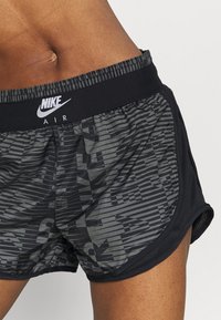 Pantalones cortos Nike Air en negro y gris, con un diseño estampado de rayas horizontales y logo. Cintura de elastano para mayor comodidad.