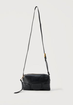 Zwart gestructureerde leren crossbodytas met verstelbare riem, gouden gesp en ritssluiting, afgebeeld tegen een effen witte achtergrond.