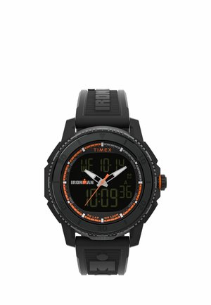 Černé digitální sportovní hodinky Timex Ironman s oranžovými akcenty, zobrazující datum, čas a stopky na černém pryžovém pásku.