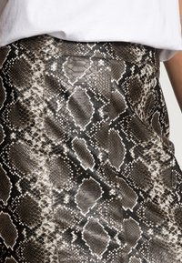Saia com padrão de píton, apresentando tons de preto, cinza e branco. Feita de material texturizado, com um design ajustado e detalhe na costura traseira.