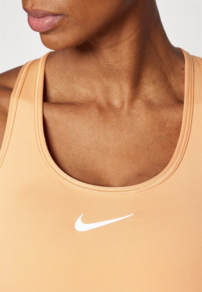 Hellorange Sporttanktop mit rundem Ausschnitt und sichtbaren Nähten. Mit einem weißen Nike-Logo in der Mitte der Vorderseite.