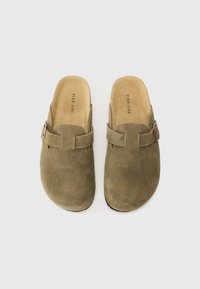 Olívovo zelené semišové dreváky s plochou podrážkou, otvoreným zadkom a remienkom cez priehlavok so strieborným prackou.