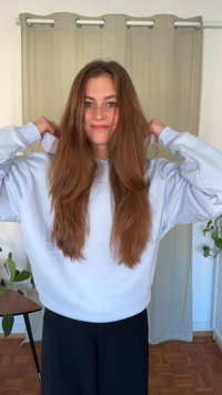 Hanorac albastru deschis cu șnur și manșete striate, asortat cu pantaloni negri. Părul este lung și ondulat, căzând în valuri pe umeri.