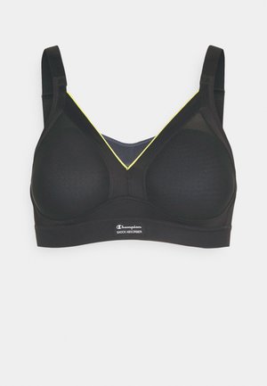 Reggiseno sportivo nero con superficie texturizzata, design a forma di V, spalline regolabili e dettagli gialli attorno al collo. Presenta un'etichetta con il logo.