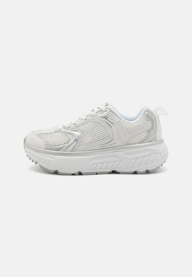 Zapatos deportivos blancos con parte superior de malla, cuello acolchado y suela texturizada. Presenta detalles del logo y diseño con cordones para un ajuste seguro.