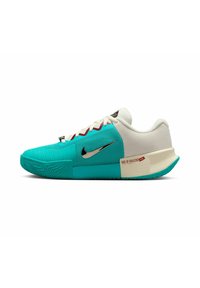 Zapatilla deportiva en turquesa y blanco con paneles texturizados, logo de Nike en negro, cordones rojos y un distintivo detalle en el talón. Diseño angular y patrón de agarre.