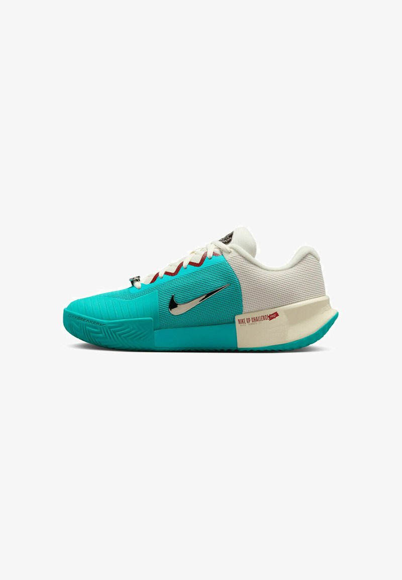 Zapatilla deportiva en turquesa y blanco con paneles texturizados, logo de Nike en negro, cordones rojos y un distintivo detalle en el talón. Diseño angular y patrón de agarre.