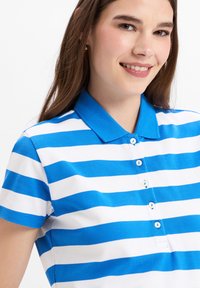 Blauwe en witte gestreepte poloshirt met een kraag, korte mouwen en vijf knopen aan de voorkant; gladde katoenen textuur.