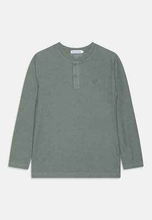 T-shirt Henley vert côtelé à manches longues avec deux boutons et petit logo cK brodé sur la poitrine.