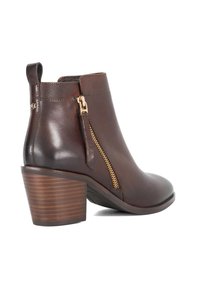 Bottine en cuir marron avec un talon carré, fermeture éclair sur le côté et détails texturés. Comprend une poignée en boucle pour un enfilage facile.