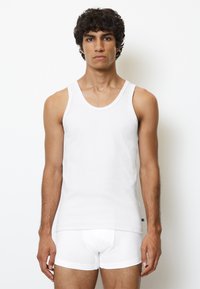 Camiseta sin mangas de algodón blanca con escote bajo y bragas blancas. Diseño ajustado con textura suave y sin patrones o acentos visibles.