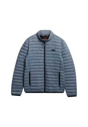 Hellblaue gesteppte Jacke mit schwarzem Reißverschluss und zwei Reißverschlusstaschen, Stehkragen und kleinem Logo-Patch auf der Brust.