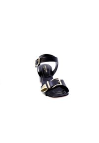 Sandalo con tacco nero caratterizzato da una larga fascia anteriore e una fascia alla caviglia con una fibbia dorata, texture liscia e un tacco modesto.