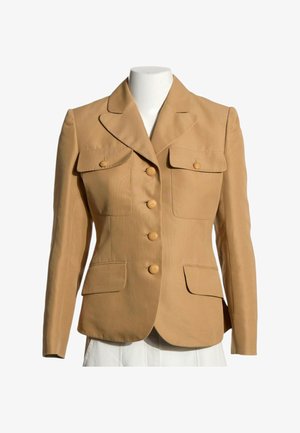 Blazer entallado color marrón claro con cuatro botones frontales, dos bolsillos delanteros con solapas y botones, y dos bolsillos inferiores con solapas en un maniquí blanco.