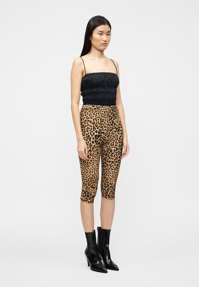 Μαύρο κοντό τοπ με ρυτιδωμένη υφή, συνδυασμένο με εφαρμοστά κολάν λεοπάρ μοτίβο. Το μοντέλο φοράει μαύρες μπότες με τακούνι. Απλό, ουδέτερο φόντο.