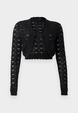 Cardigan noir à manches longues en maille raccourcie avec un motif ajouré ouvert et une fermeture à nouer sur le devant, sur un fond uni.