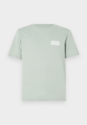 Camiseta de algodón de color verde claro con escote redondo y mangas cortas. Presenta un logotipo blanco "JACK & JONES" impreso en el lado izquierdo del pecho.