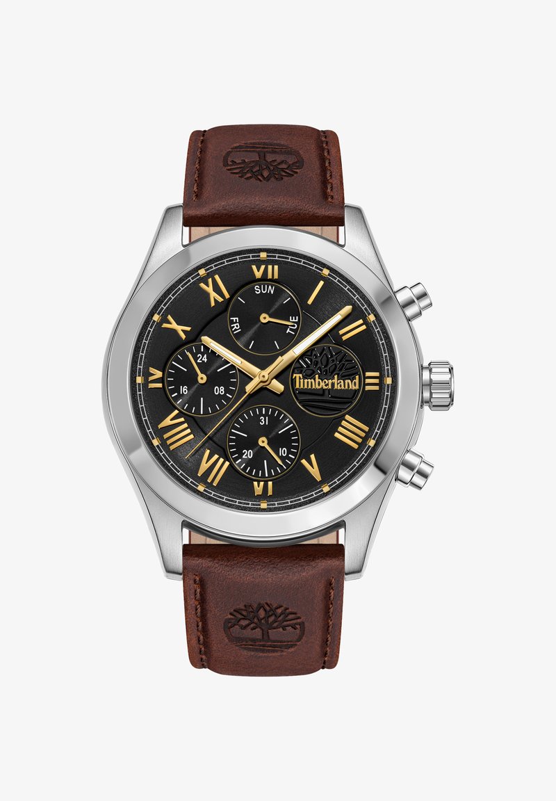 Montre argentée métallique avec un cadran noir, des chiffres romains dorés, des sous-cadrans, et un bracelet en cuir marron embossé d'un logo d'arbre.