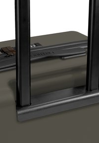 Grauer Koffer mit einem robusten schwarzen Griff, ausgestattet mit einem strukturierten Reißverschluss und einem Schlossmechanismus. Glatte Oberfläche mit minimaler Gestaltungsdetail.