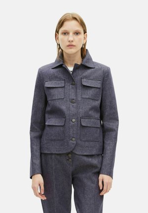 Veste bleu foncé au design structuré avec un col, quatre poches avant et une fermeture à boutons. Fabriquée en tissu texturé.