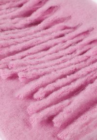 Rosa strikket stof med hævede, teksturerede tråde, der skaber et bølgelignende mønster. Blød, fuzzy tekstur med varieret tykkelse. 