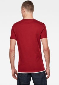 Red cotton T-shirt with short sleeves, round neckline, and a clean finish. The back shows a smooth texture with subtle stitching details.